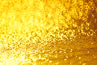 Closeup of golden shimmering reflections off water.