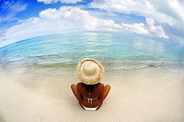 Hawaii, Woman sitting on beach in remote tropical location.