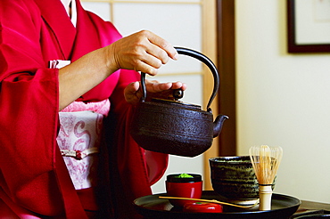 Close up of geisha pouring tea at tea ceremony.