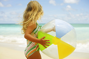 Hawaii, Oahu, little girl poses on beach with beach ball.