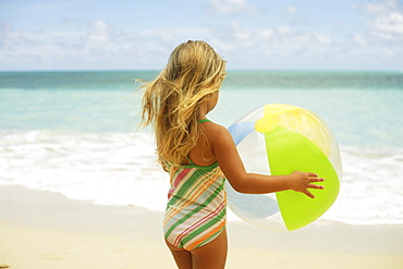 Hawaii, Oahu, little girl poses on beach with beach ball.