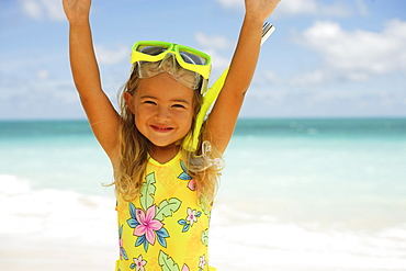 Hawaii, Oahu, little girl poses on beach with snorkel.