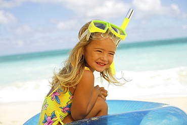 Hawaii, Oahu, little girl poses on beach with snorkel.