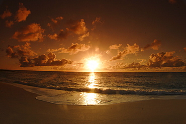 Hawaii, Oahu, North Shore, bright sun reflecting on ocean as it sinks low in the sky, golden light.