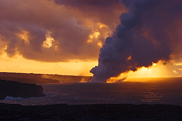 Hawaii, Big Island, Kalapana, Steam cloud from lava entering Pacific Ocean from Kilauea at sunset.