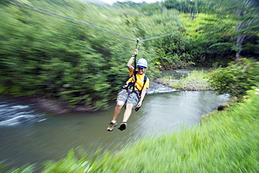 Hawaii, Kauai, girl on a valley zipline tour over a stream.