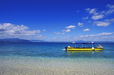 Fiji, South Sea Island, Local person in yellow boat, crystal clear ocean water.