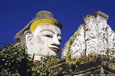 Burma (Myanmar), Mandalay, Close-up of Colossal, head of Buddha against blue sky.