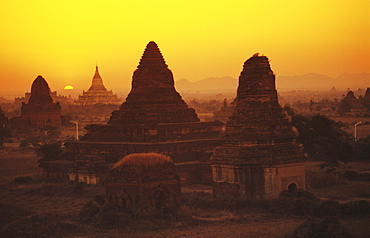 Burma (Myanmar), Bagan, Shwesandaw Paya, overview of temples against orange sky and setting sun.