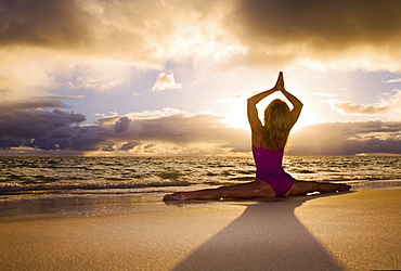 Hawaii, Oahu, Lanikai, woman doing yoga on the beach at sunrise.