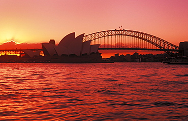 Australia, New South Wales, Sydney, Opera House and Harbour Bridge, bright red and pink sunset.