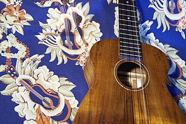 Detail of handmade koa ukulele on aloha print background