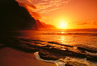 Hawaii, Kauai, NaPali Coast at sunset, bright orange sky and calm ocean.