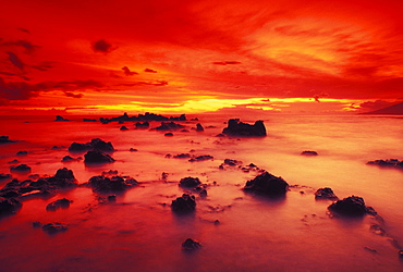 Hawaii, Maui, Lava rock beach at sunset with dramatic red yellow sky and shore