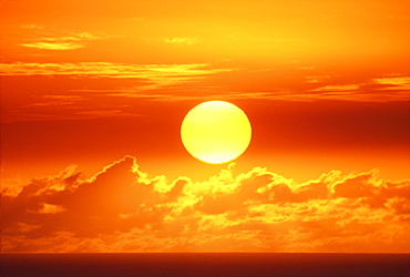 Hawaii, Oahu, Waikiki, View of huge orange sun sinking towards the horizon.