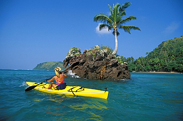 Fiji, Kadavu Islands, Caucasian woman kayaking along beautiful coastline.