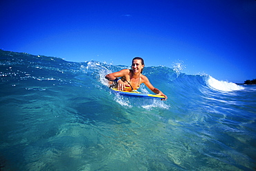 Hawaii, Woman body boarder Claudia Cox smiling as she catches wave