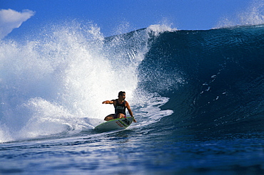 Johnny Boy Gomez, riding a wave, arm extended, turns as wave curls with whitewater