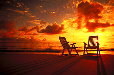 Beach chairs along shoreline at twilight, amazing sunset