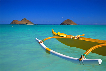 Hawaii, Oahu, Lanikai, Outrigger canoe in turquoise ocean Mokulua Islands background 