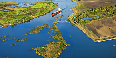 Agriculture - Aerial view of an ocean going grain ship transiting the deep water channel in the Sacramento-San Joaquin River Delta between the Port of Sacramento and the San Francisco Bay and Pacific Ocean / California, USA.