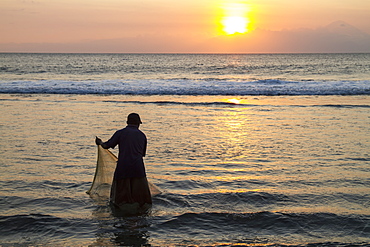 Fisherman casting his net in the ocean at sunset, Mangsit, Lombok, West Nusa Tenggara, Indonesia