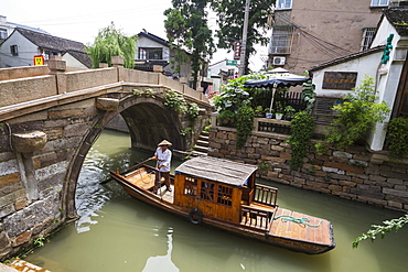 Man punting a boat by a bridge over the North-South canal by Pingjiang Road, Suzhou, Jiangsu, China