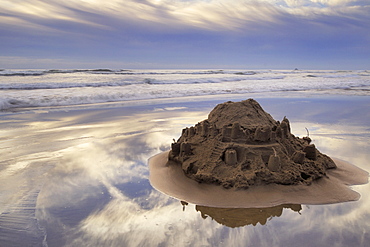 A Sandcastle Being Slowly Washed Away By The Incoming Tide, Cannon Beach, Oregon