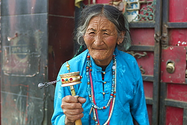 Elderly woman spins prayer wheel, Manigange, Sichuan, China