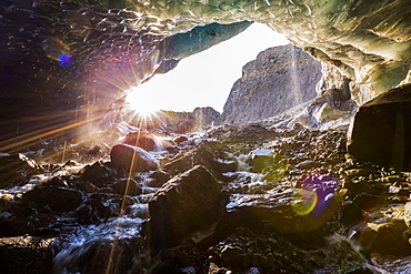 The sun shines into a cave beneath the ice of Root Glacier in Wrangell-St. Elias National Park; Alaska, United States of America