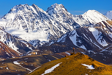 Snowy, unnamed mountains form the backdrop behind a backpacker exploring the backcountry of Denali National Park; Alaska, United States of America