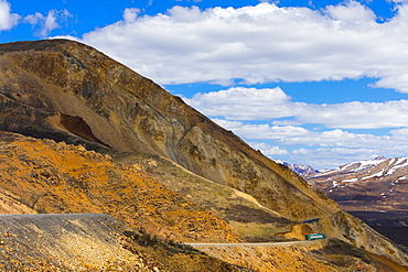 A shuttle bus winds around cliffs near Polychrome Pass in Denali National Park; Alaska, United States of America