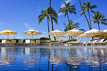 Halekalani Pool at Waikiki with palm trees and umbrellas reflected in the water, Waikiki, Oahu, Hawaii, United States of America