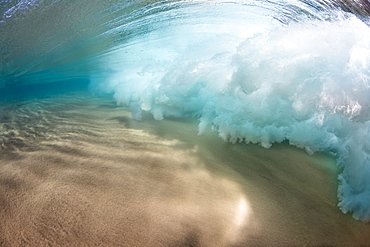 Underwater view of a breaking wave as the surf crashes over a sandy bottom off the island of Maui, Maui, Hawaii, United States of America