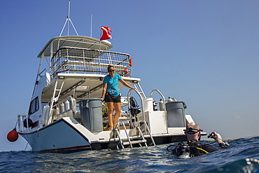 Scuba diver being greeted by dive boat captain at end of dive off the Kona coast, Island of Hawaii, Hawaii, United States of America