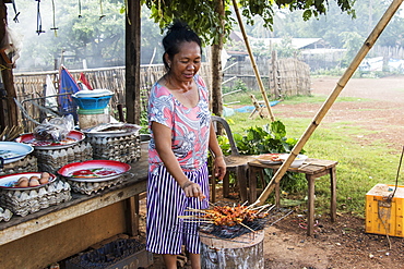 Woman barbecuing satay, Pha Suam, Bolaven Plateau, Champasak, Laos