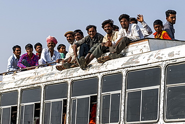 A bus full of people and passengers riding on the roof, Jaisalmer, Rajasthan, India