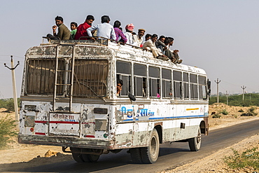 A bus full of people and passengers riding on the roof, Jaisalmer, Rajasthan, India