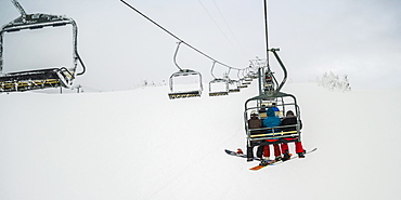 Skiers on a chairlift at Sun Peaks ski resort, Kamloops, British Columbia, Canada