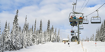 Skiers on a chairlift at Sun Peaks ski resort, Kamloops, British Columbia, Canada