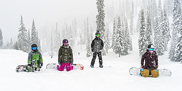 Snowboarders kneeling and resting at Sun Peaks Resort, Kamloops, British Columbia, Canada