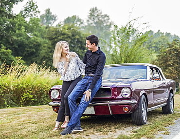 A young couple standing with a vintage sports car, Bothell, Washington, United States of America