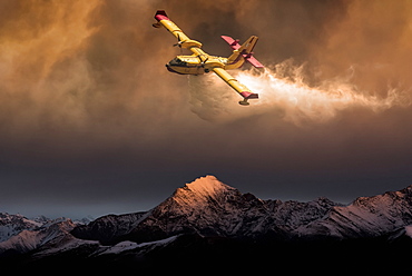 An aircraft dropping water on a forest fire in the mountains below, composite image