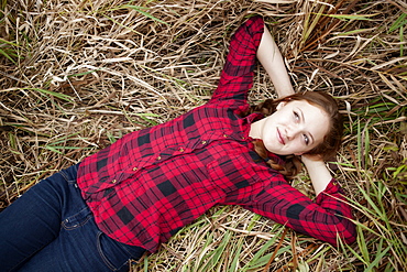 Portrait of a girl lying in a field of tall grass looking up, Toronto, Ontario, Canada