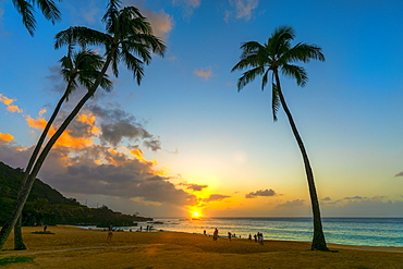 Tourists enjoying the beach at Waimea Bay Beach Park at sunset, Oahu, Hawaii, United States of America