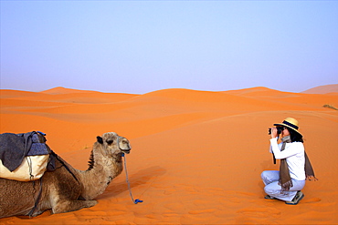Tourist in desert taking photographs, Merzouga, Morocco, North Africa, Africa