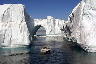 Icebergs in Disko Bay, natural arch and motorboat, UNESCO World Heritage Site, Ilulissat (Jakobshavn), Greenland, Denmark, Polar Regions 