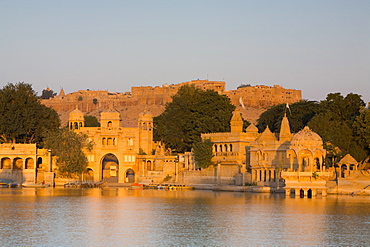 Jaisalmer Fortress and Gadsisar Lake illuminated at sunrise, Jaisalmer, Rajasthan, India, Asia