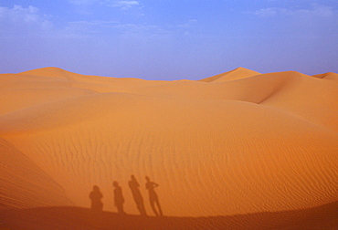 Tourists climbing up a sand dune in the Sahara Desert, Morocco