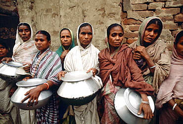 The poor queuing for food outside Mother Teresa's Mission in Calcutta, India.  The women are carrying metal pots in which to carry the food back to their families.